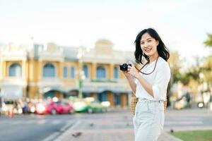porträtt skön asiatisk kvinna resande med kamera utforska gata på sommar semester i Bangkok, thailand foto