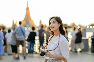 porträtt ung skön asiatisk kvinna leende medan resa på wat en springtur solnedgång se punkt, Bangkok, thailand. foto