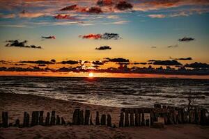 färgrik solnedgång över de putsa baltic hav med mörk himmel moln och vågbrytare foto