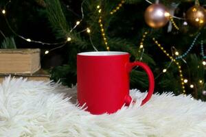tom röd råna med jul träd på bakgrund, matta te eller kaffe kopp med jul och ny år dekoration, horisontell falsk upp med keramisk råna för varm drycker, tom gåva skriva ut mall foto