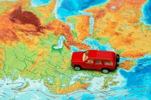 röd leksak bil på de fysisk Karta av de värld i Europa mot de öst foto