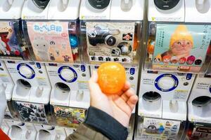 Osaka, Japan, 2018 - hand av turist innehav och visa kapsel leksak på suddigt gashapong försäljning maskin. gashapong är ett av försäljning maskindispenserad kapsel leksaker populär i japan. foto