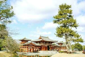 byodoin japansk buddist tempel hall med många turister komma till besök på ljus blå himmel och moln. foto