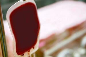 närbild blod i en väska hängande på en Pol är överföra blod till en sjuk nyfödd bebis i en sjukhus. foto