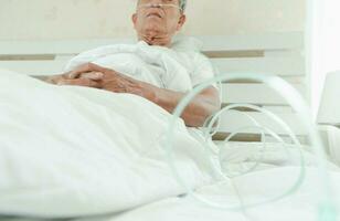 ledsen senior man liggande på de sjukhus säng och med en nasal andas rör för behandling andningsorganen. begrepp av hälsa vård för de äldre, karantän coronavirus covid-19 foto