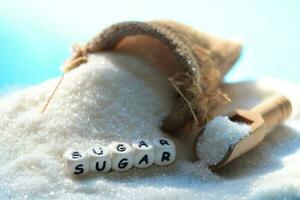 vit socker för mat och sötsaker efterrätt godis högen av ljuv socker kristallin granulerad, socker på säck och trä- bakgrund foto