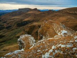 gryning se av bermamyt platå rocks. bergen på de kant av en klippa i de distans på dramatisk morgon. atmosfärisk landskap med silhuetter av berg. karachay-cherkessia, Kaukasus, Ryssland. foto