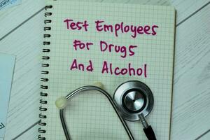 begrepp av testa anställda för läkemedel och alkohol skriva på en bok med stetoskop isolerat på trä- tabell. foto