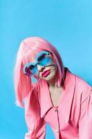 glamorös kvinna i blå glasögon bär en rosa peruk isolerat bakgrund foto