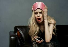 full blond kvinna i sömn mask med mobil telefon fotografi modell foto