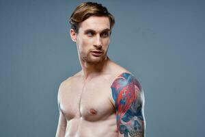 man med tatuering naken torso sport kondition grå bakgrund porträtt foto
