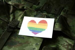hjärta teckning i regnbåge färger kort på kamouflage militär ryggsäck, begrepp för stödjande och kallelse ut Allt människor till respekt kön mångfald av människor och till fira lgbtq i stolthet månad foto
