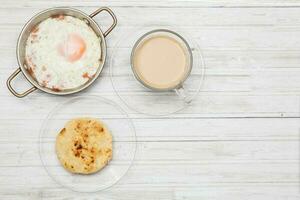 friterad ägg, kaffe och arepa på trä- vit tabell foto