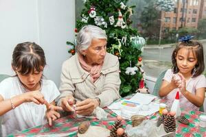 liten flickor har roligt medan framställning jul nativity hantverk med deras mormor - verklig familj foto