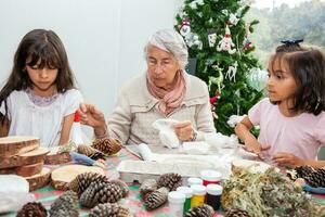 liten flickor har roligt medan framställning jul nativity hantverk med deras mormor - verklig familj foto