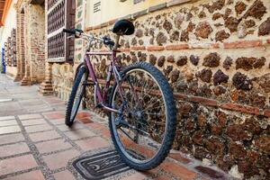 cykel parkerad Nästa till ett gammal sten vägg på de kolonial stad av santa fe de antioquia i colombia foto