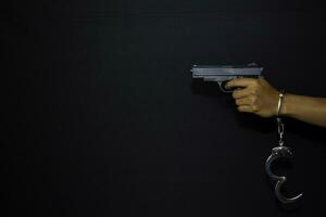 asiatisk man innehar pistol och handklovar hängande på en hand isolerat på svart bakgrund foto