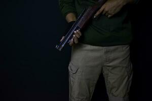 asiatisk man innehar en pistol. pistol i hans hand isolerat på svart bakgrund. foto