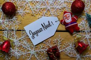 joyeux noel skriva på märka med trä- bakgrund. den betyder glad jul. ram av jul dekoration. foto