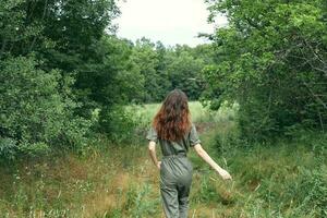 Lycklig brunett kvinna i overall på en äng i de skog tillbaka se foto
