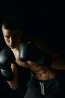 idrottare i svart boxning handskar på en mörk bakgrund kroppsbyggare kondition foto