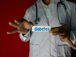 en läkare stående, håll de diabetes papper text på röd bakgrund. medicinsk och sjukvård begrepp. foto