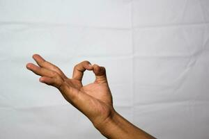 stänga upp asiatisk man visar hand gester den betyder ok isolerat på vit bakgrund foto