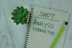 SWOT - analys styrkor skriva på en bok isolerat på trä- tabell. foto