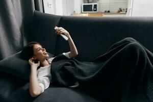 Lycklig kvinna med en mobil telefon i främre av henne ögon lögner på en bekväm mjuk soffa foto