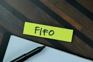 fifo skriva på klibbig anteckningar isolerat på trä- tabell. foto