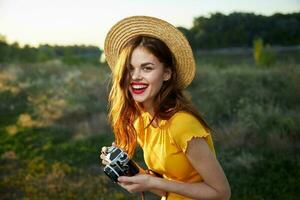 glad kvinna med kamera bär hatt utomhus färsk luft fritid foto