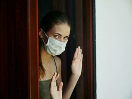 kvinna i medicinsk mask ser ut de fönster låsning missnöje, låsning foto