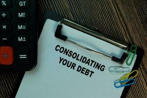 konsolidera din skuld skriva på en pappersarbete isolerat på trä- tabell. finansiera begrepp foto