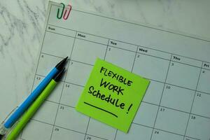 flexibel arbete schema skriva på klibbig anteckningar isolerat på kontor skrivbord. foto