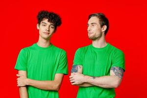 två män i grön t-tröjor är stående sida förbi sida kommunikation foto