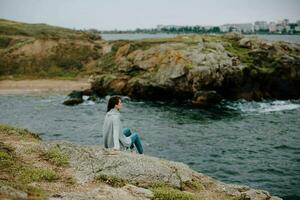 Söt kvinna sittande på de kust Tröja landskap oförändrad foto