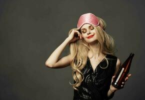 skön blond med en rosa sömn mask och en flaska av öl i henne hand foto