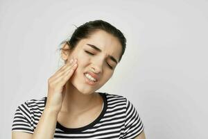 emotionell kvinna innehav på till ansikte tandvärk hälsa vård ljus bakgrund foto