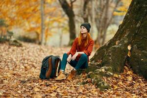 ung kvinna i höst skog och gul löv ryggsäck modell resa landskap foto