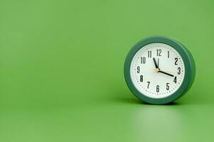 klocka dyrbar tid larm klocka på grön bakgrund begrepp av tid arbetssätt med tid foto