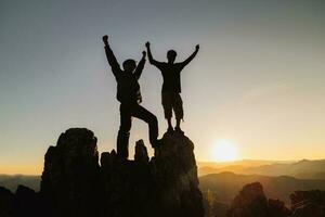 silhuett av två man med Framgång gest stående på de topp av berg. företag lagarbete begrepp. foto