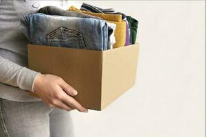 kvinna förpackningar kläder i lådor för donera. foto