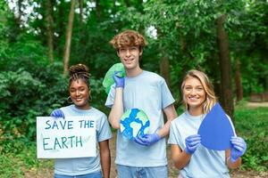 olika grupp av människor plockning upp skräp i de parkera volontär- gemenskap service. Lycklig internationell volontärer innehav plakat med 'spara de jorden' meddelande. foto