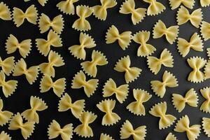 rå pasta farfalle mönster på svart bakgrund. foto