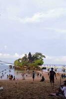 balekambang strand se med massor av turister spelar i de sand foto
