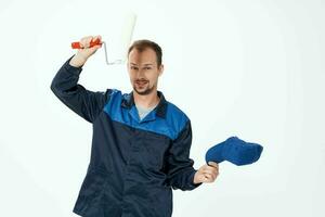 en man i en arbetssätt enhetlig en vält för målning väggar i hans händer dekoration reparera foto
