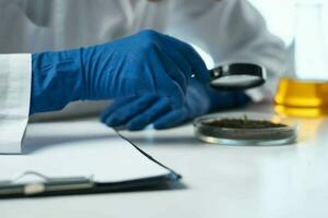 kvinna laboratorium assistent ser genom en förstoringsglas biologi uppföljning kemisk lösning foto