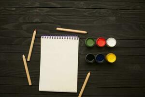 vattenfärg målarfärger pennor anteckningsblock teckning verktyg konst mörk trä bakgrund foto
