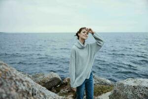 skön kvinna tröjor molnig hav beundrande natur kvinna avkopplande foto
