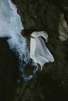 kvinna i lång vit klänning våt hår liggande på en klippig klippa sommar semester begrepp foto